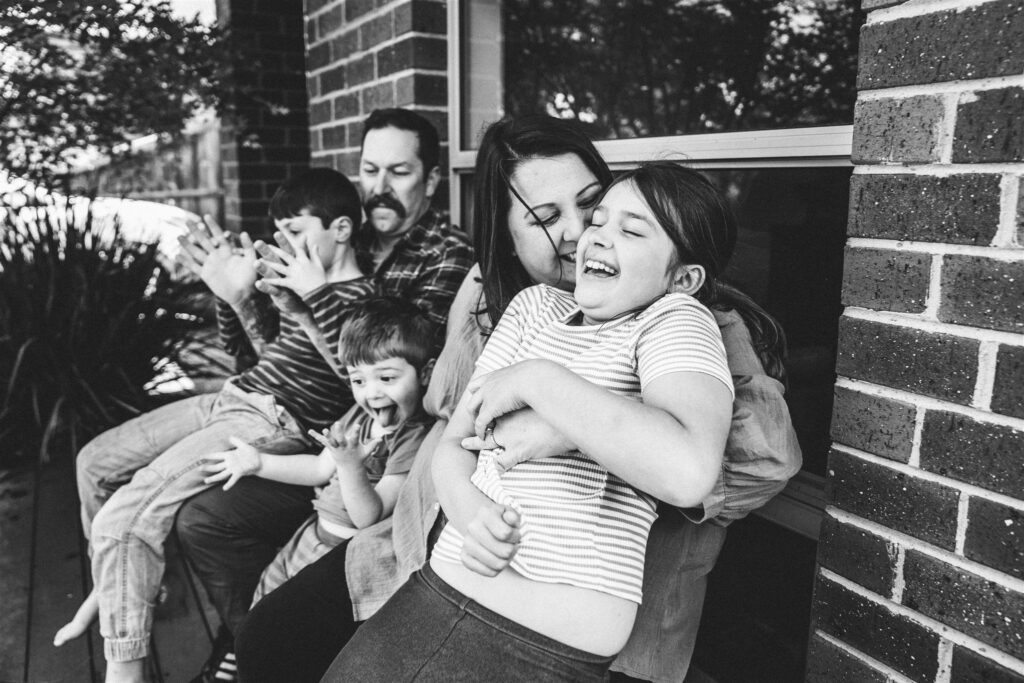 Family laughing together outside of their home.