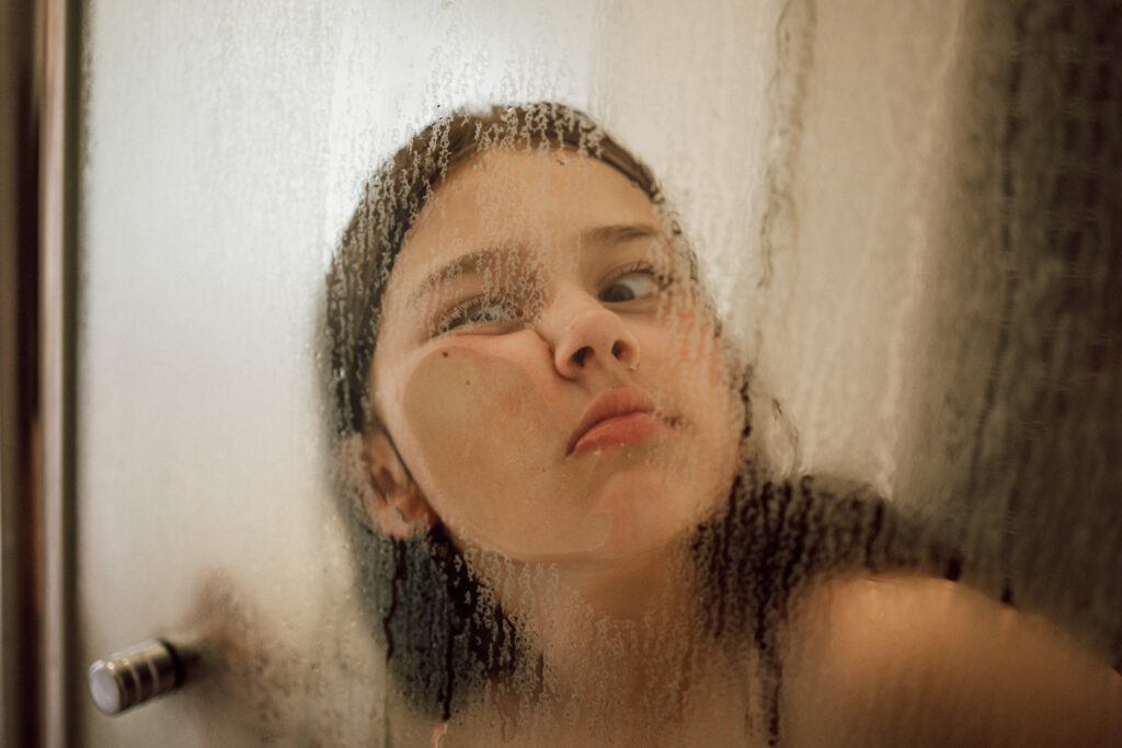 Family Lifestyle Photography: Child pressing face against shower glass.