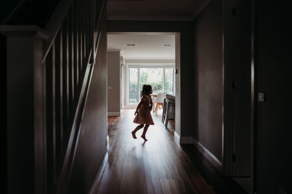 Girl twirling in corridor of her home.