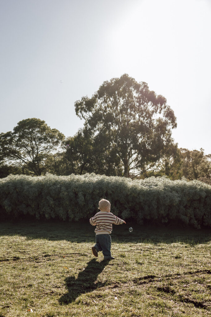 Young boy chasing single bubble.