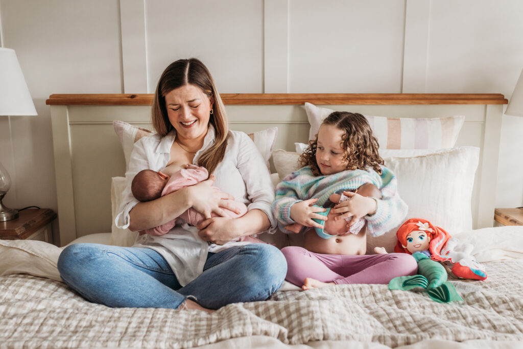 Child with their toy baby pretending to be a mum too, breastfeeding her child. 