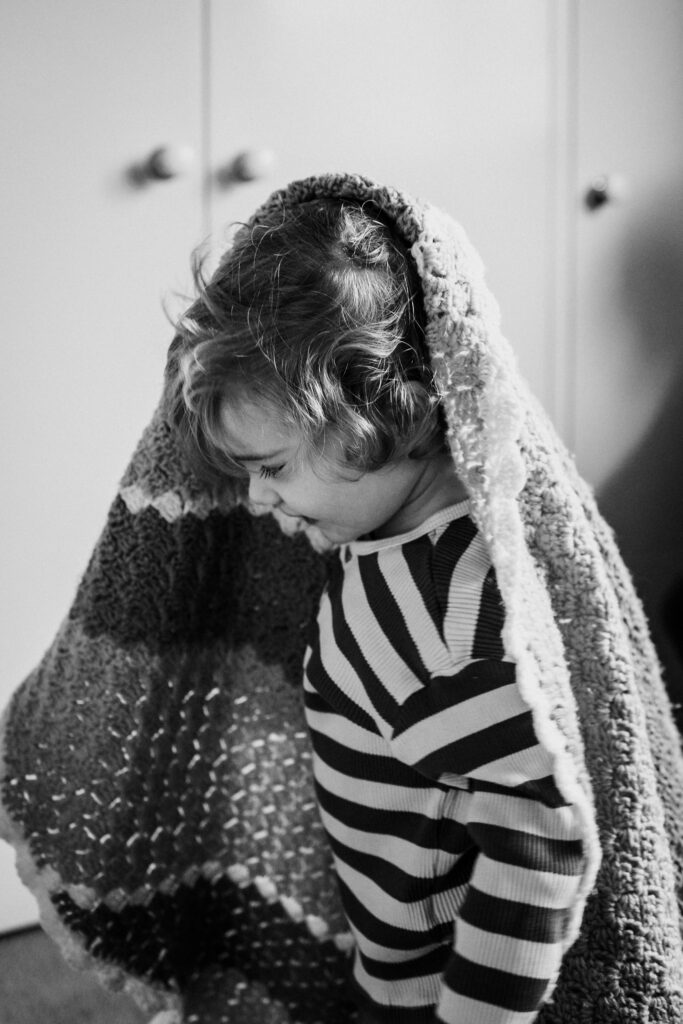 what to wear for family photos. Child wearing beloved chunky blanket over head
